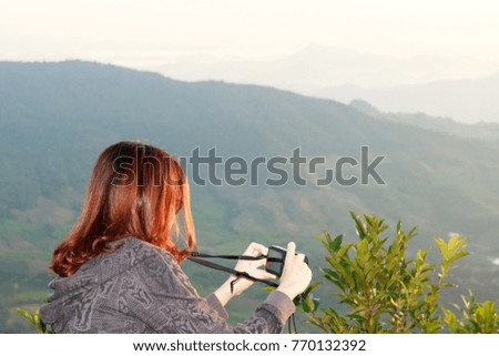 young woman traveler taking a photo on mountain and looking fog in morning landscape.