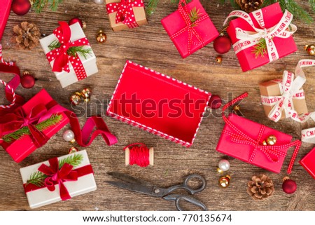 Christmas gift giving - pile of wrapped in red and white paper christmas gift boxes with open and empty one on wooden background