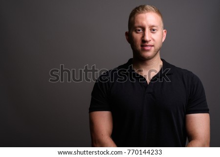 Studio shot of man with blond hair wearing black shirt against gray background