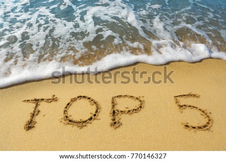 The word "top 5" is written on the golden sand of the beach by the sea. Concept - the five best beaches, tours or ways to relax in the south. Royalty-Free Stock Photo #770146327