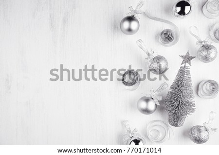 Christmas silvery glitter decorations - balls, curl tapes, flower on white wood board.