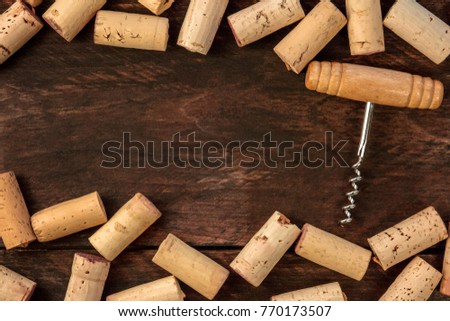 A photo of an old-fashioned corkscrew with corks, shot from above on a dark wooden background texture with a place for text. A design template for a wine list or a tasting invitation