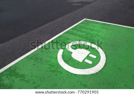 Free green colored electric vehicle parking station painted on asphalt floor.