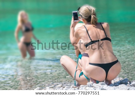 Women in swimsuits are photographed on the beach