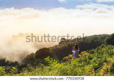 Freedom traveler woman taking photo with mobile phone on the beautiful nature view in fog and cloud mountain