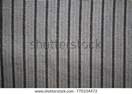 Stripe of black color on gray fabric background.