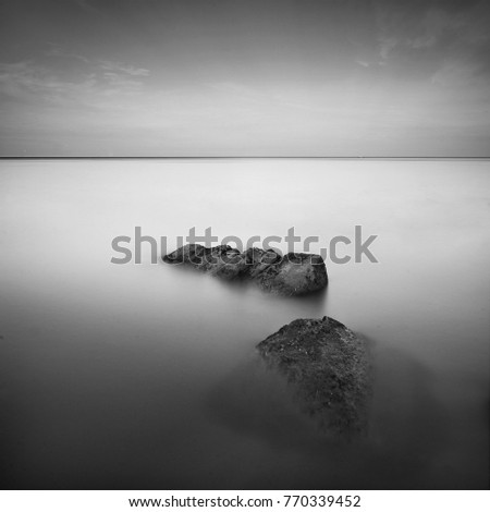 Fine art image in black & white of sea rock at Pinang beach, Malaysia. Soft Focus due to long exposure.