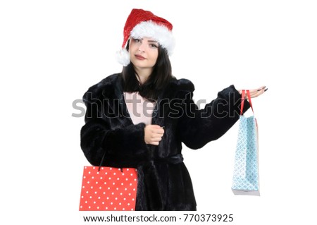 Brunette girl in black fur coat in santa hat with shopping bags on isolated background, christmas shopping, sale santa claus

