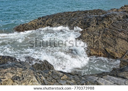 Waves with foam beat the rocks into the Arabian sea at Vagator beach in North Goa.India