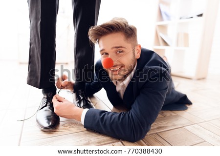 A man under the table to tie laces to his business colleague. This is a joke on April 1. He jokes on his friend. He has a good mood. Royalty-Free Stock Photo #770388430