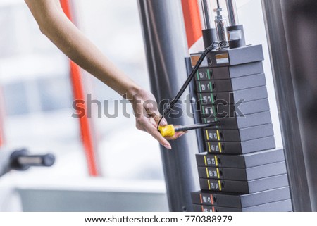 cropped shot of woman adding weight bars on gym machine