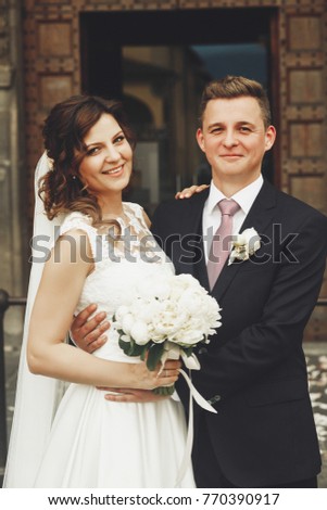 Cheerful wedding couple leans to each other tender posing outside somewhere in Italy