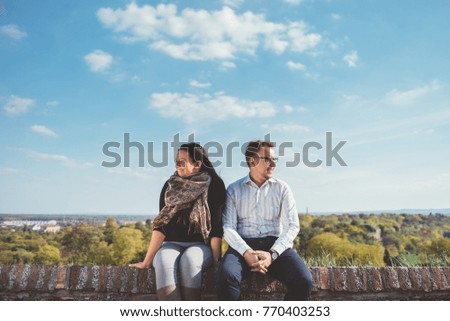 Couple sitting on wall and looking in opposite directions