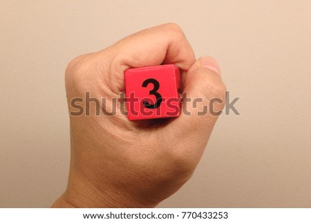 Hand holding number three wooden cubic,number 3