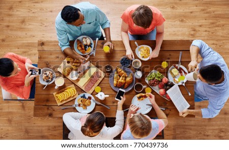 breakfast, technology and family concept - group of people with smartphones eating and photographing food at table