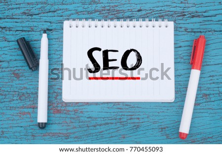 Marker pens and notebook written SEO over wooden background