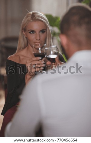 A beautiful, loving couple enjoys dinner and wine.
