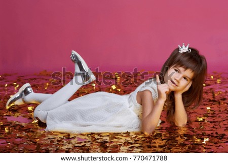 Little girl in a white dress on a pink background with a gold confetti