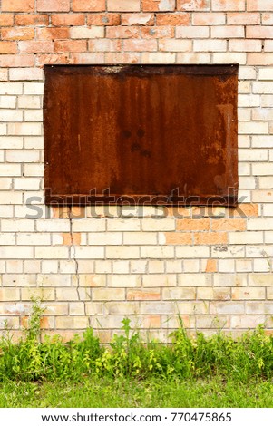 Yellow and red brick wall with a boarded window