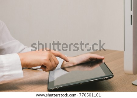 Close up hands touching screen of woman using old tablet on her desk