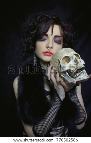 Pretty gothic girl with skull over dark background