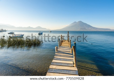Wooden pier at Lake Atitlan on the shore at Panajachel, Guatemala.  With beautiful landscape scenery of volcanoes Toliman, Atitlan and San Pedro in the background.