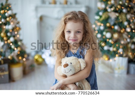 Happy little girl at home sitting near Christmas tree selebrating ney year and enjoying warm cozy Xmas evening. Happy Family consept.