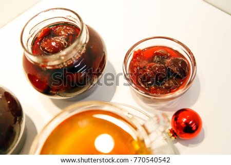 Herbal tea in a glass cup from the willow-tea (kiprej, Onagraceae) and  Homemade jam in jars and rosettes.
