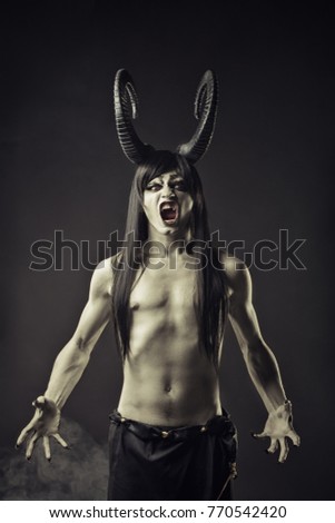 Angry horned devil posing over dark background