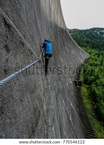 An alpinist climbing at the schlegeis dam in the austrian alp valley zillertal in tyrol at the via ferrata sport rope route