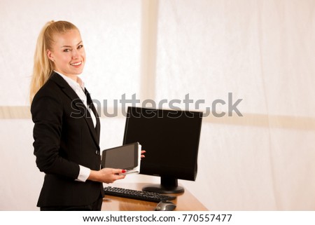 Beautiful young business woman surfing the web on tablet checking data in her office