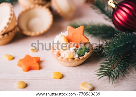 Mini crab salad tarts on wooden background. Christmas holiday buffet table served by canape snacks. Red baubles, fir-tree branches
