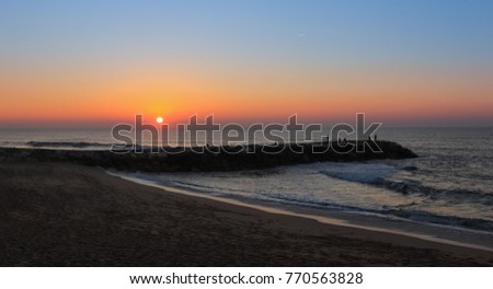 Amazing sunset over a beach with a jetty. Ericeira , Portugal