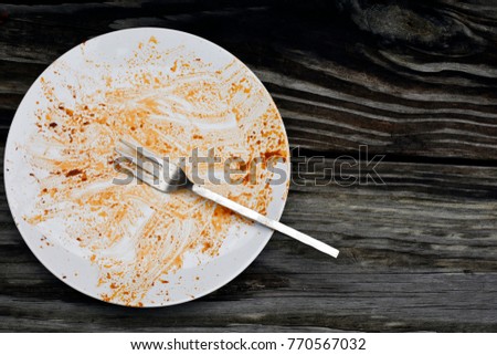 top view of dirty white dish and fork with pasta sauce 