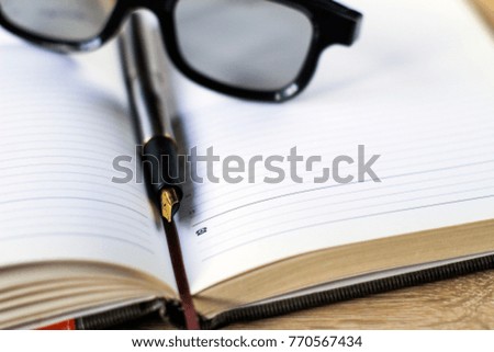 fountain pen and glasses lie on a notebook