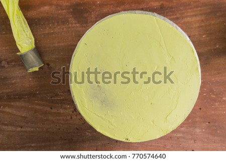 Yellow Round Sponge Cake and Pastry Bag On Wood Background.