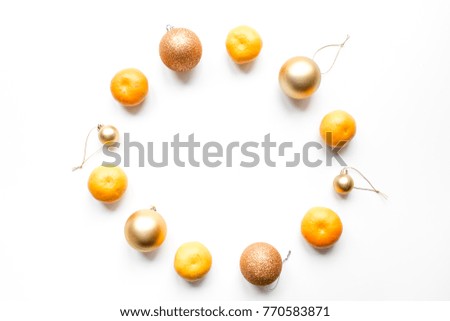 Tangerines / mandarines with peel mixed with golden brown christmas decoration balls, forming a circle. Flat lay centered symmetric image on white background.