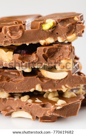 Closeup stack of luxury handmade milk chocolate bars with different nuts on white background