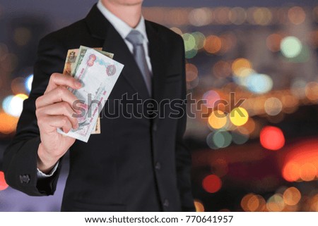 Businessman hold United Arab Emirates Dirham (AED) money on the bokeh night cityscape background as business, trade, investment and income concept