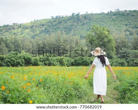 Traveler woman standing in flower garden with forest and mountain background.Happy asian woman white dress travel in flower park and sunshine and natural