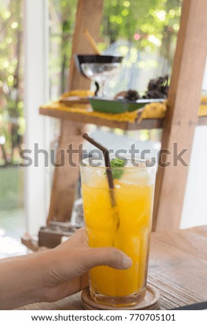 Woman hand on orange juice at table, stock photo