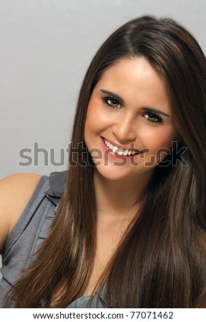 A studio close-up of a lovely young brunette with long, luscious hair and a captivating smile.