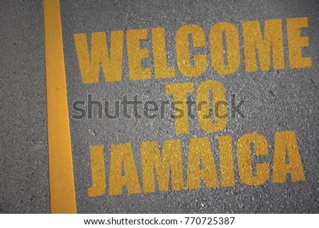 asphalt road with text welcome to jamaica near yellow line. concept