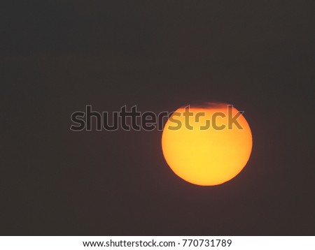 A large, red setting sun hangs under a cloud, Thailand
