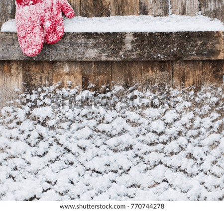 old wooden background with snow and mittens