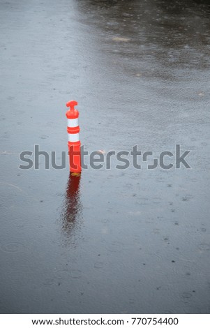 Orange traffic cone submerged in water in a flooded street