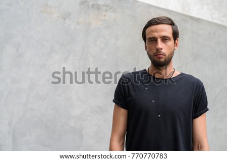 Portrait of handsome man against concrete wall in the streets outdoors
