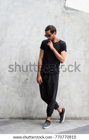 Portrait of handsome man wearing sunglasses against concrete wall in the streets outdoors