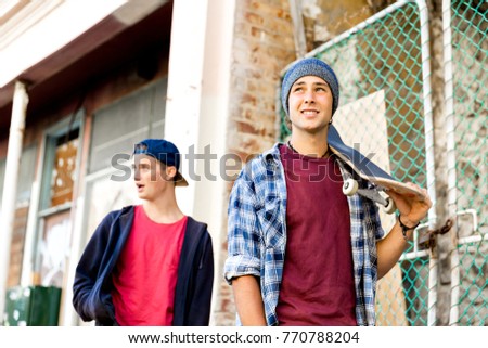 Teenage friends walking at the street with skateboards