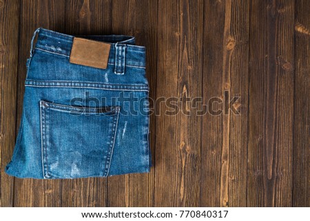 Frayed jeans or blue jeans denim collection on rough dark wooden table background, top view with copy space, old fashion style concept.
